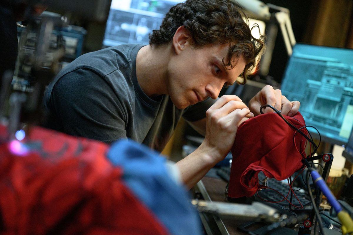 Tom Holland as Peter Parker repairing his homemade Spider-Man mask at his workbench